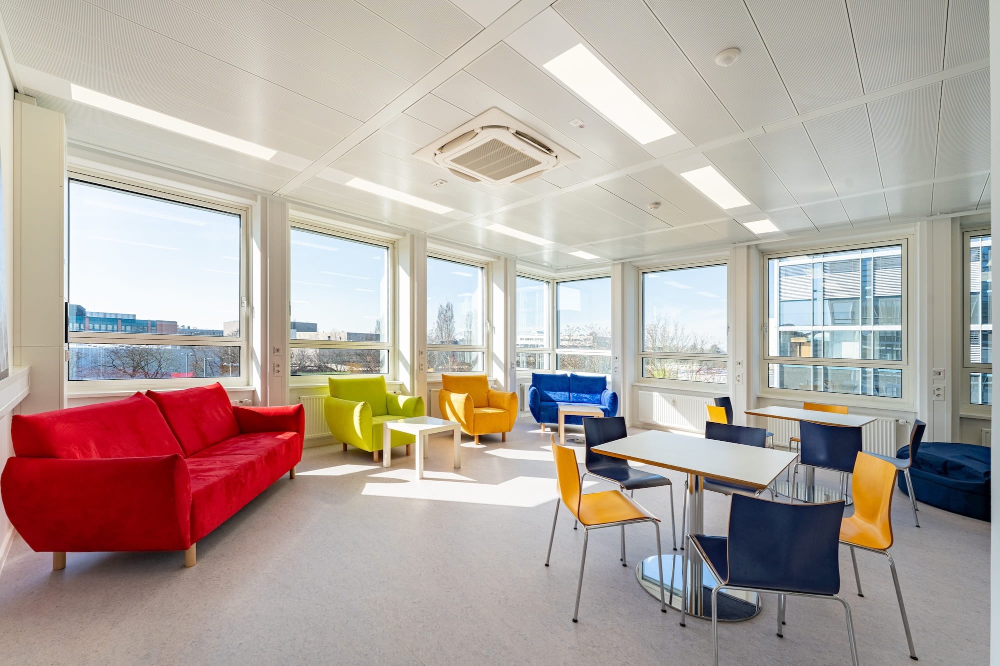 Heller Aufenthaltsraum mit LED-Deckenbeleuchtung und farbiger Lounge