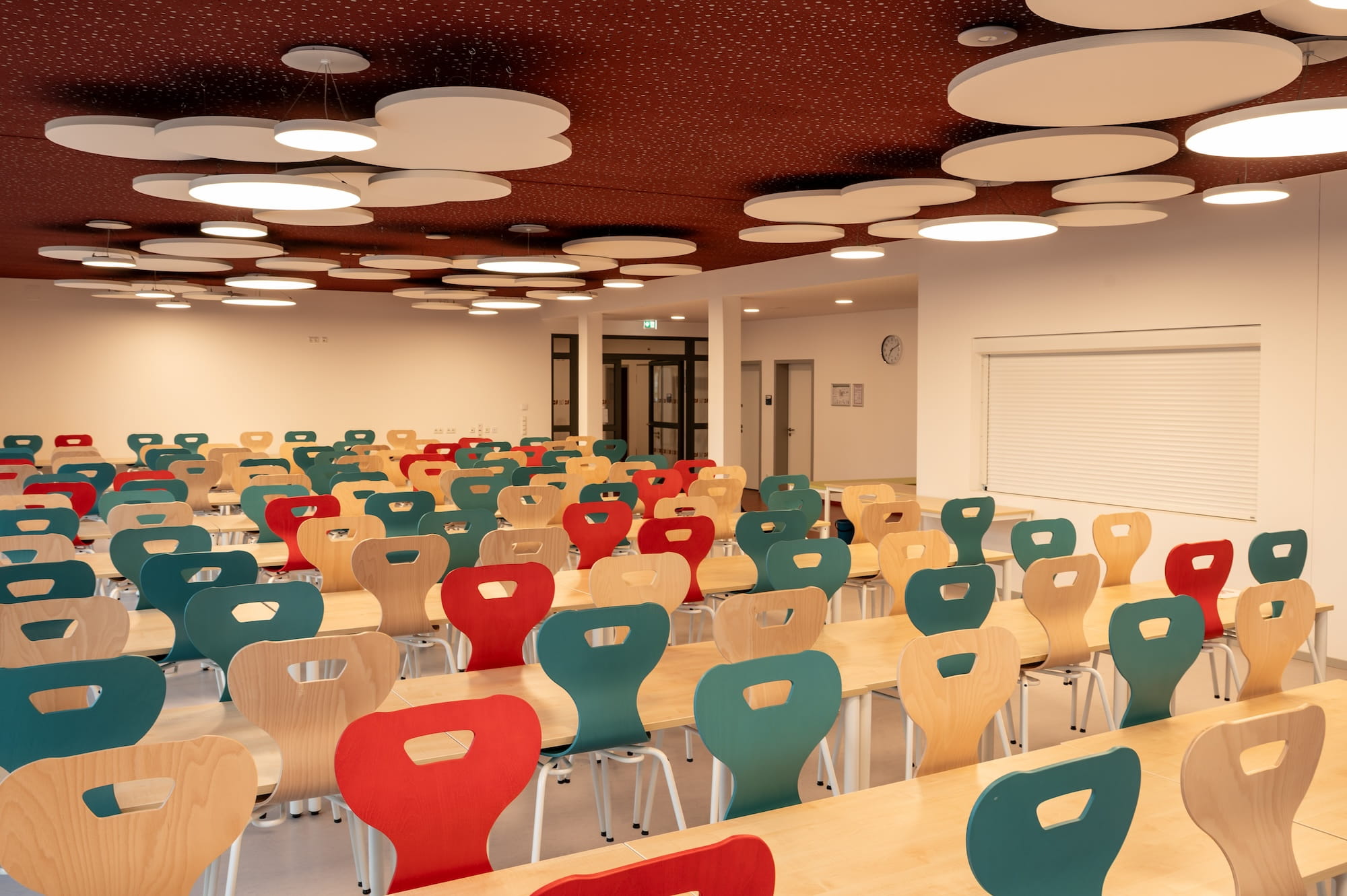 Speiseraum mit Akustik-Deckensegeln und farbigen Stühlen